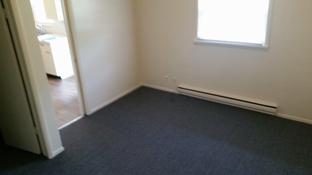 unfurnished room featuring dark carpet, a baseboard radiator, and baseboards