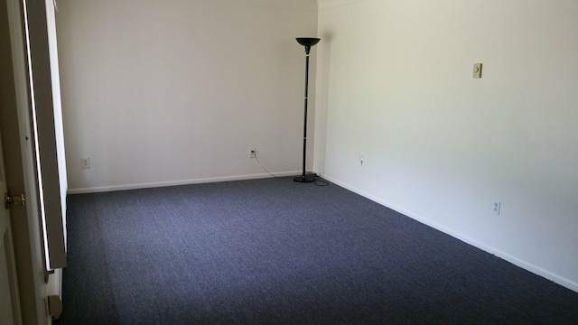 unfurnished room featuring baseboards and dark colored carpet