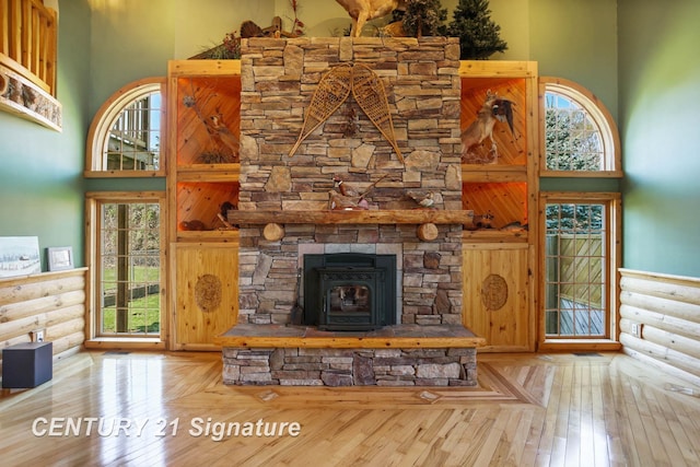4285 N Iva Rd, Hemlock, MI 48626 - unfurnished living room with a towering ceiling, rustic walls, a wood stove, and hardwood / wood-style floors