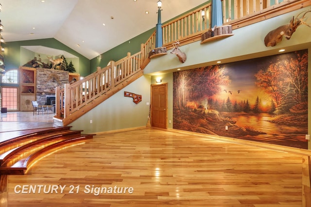 4285 N Iva Rd, Hemlock, MI 48626 - unfurnished living room with wood-type flooring, high vaulted ceiling, a stone fireplace, stairway, and baseboards