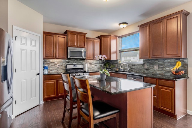kitchen featuring brown cabinetry, a sink, dark wood finished floors, and stainless steel appliances
