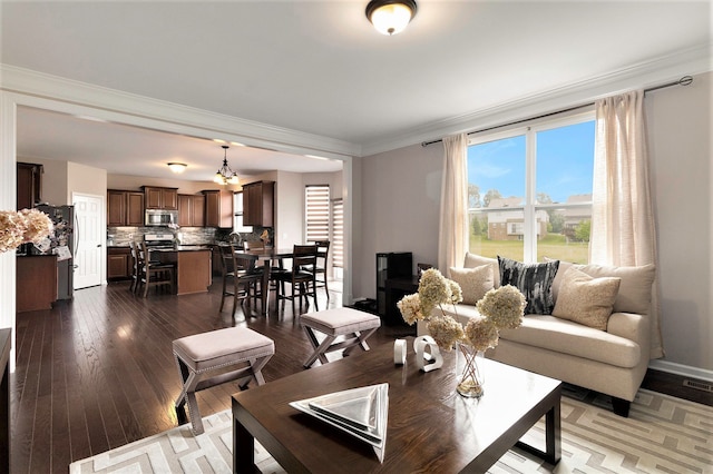 living area featuring ornamental molding and dark wood-style flooring