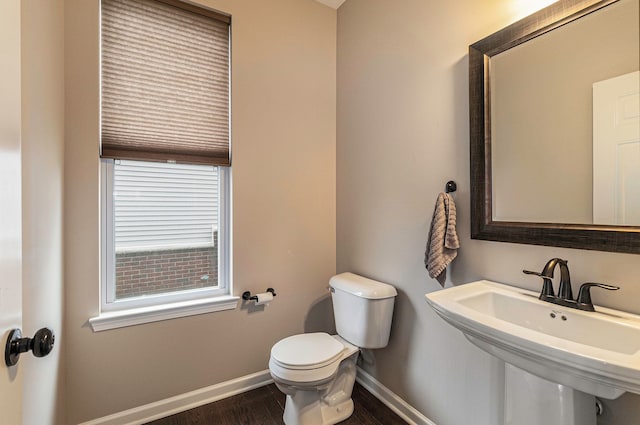 bathroom with a sink, baseboards, toilet, and wood finished floors