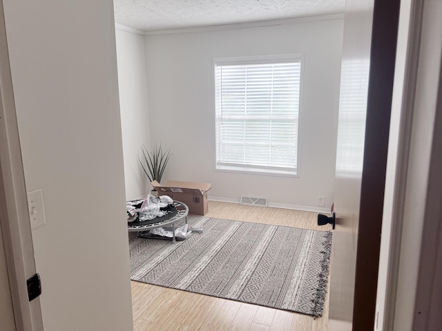 interior space featuring a textured ceiling, wood finished floors, and visible vents