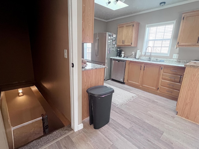 kitchen with light brown cabinets, ornamental molding, light wood-style flooring, stainless steel appliances, and a sink