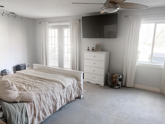 bedroom with a ceiling fan, light colored carpet, and multiple windows