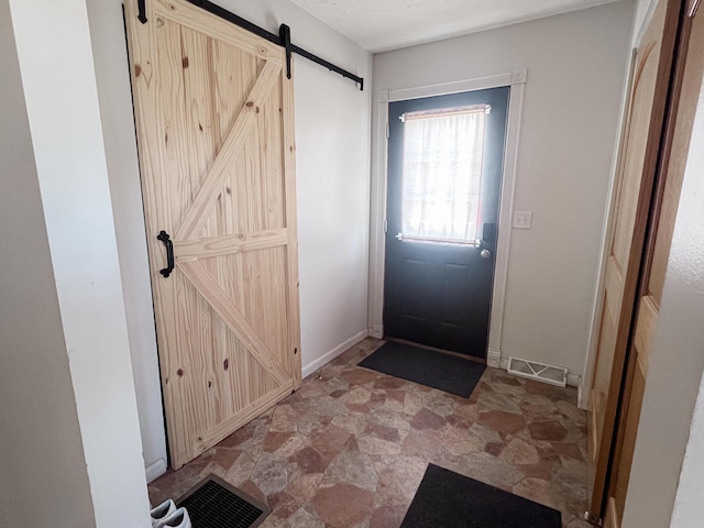 entrance foyer with a barn door, stone finish floor, and visible vents