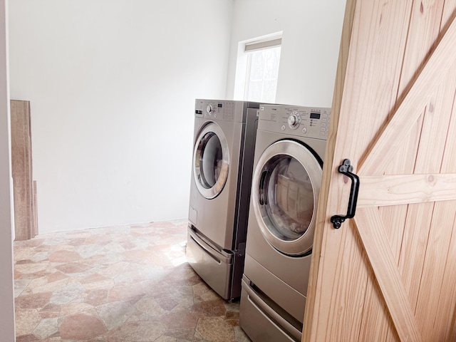 laundry room with stone finish flooring, washing machine and dryer, and laundry area