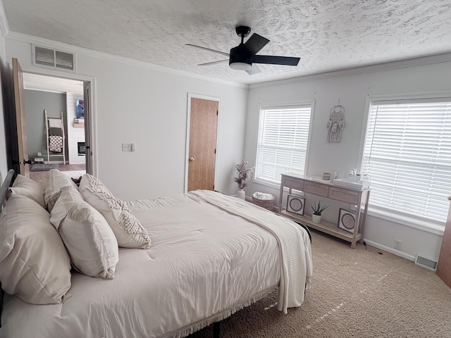 bedroom with visible vents, a textured ceiling, ornamental molding, and carpet floors