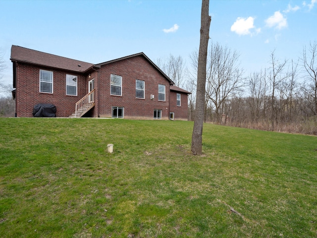 back of house with brick siding and a yard