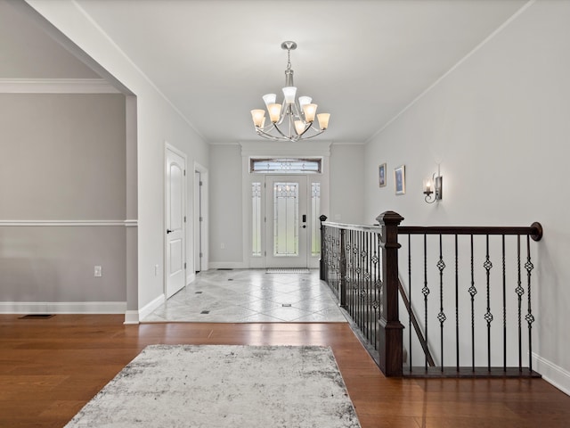 foyer entrance with an inviting chandelier, ornamental molding, wood finished floors, and baseboards