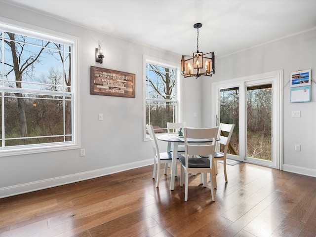 dining space with wood finished floors, a healthy amount of sunlight, baseboards, and a notable chandelier
