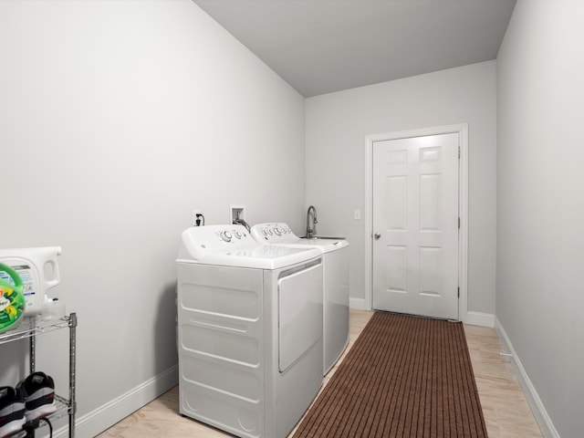 laundry area with baseboards, light wood finished floors, washer and dryer, and laundry area
