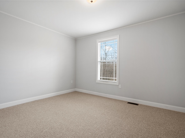 spare room featuring light colored carpet, baseboards, ornamental molding, and visible vents