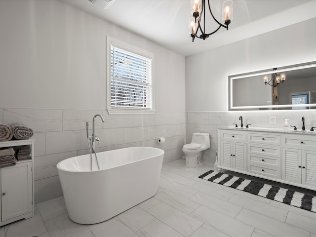 full bath with a soaking tub, toilet, tile walls, an inviting chandelier, and marble finish floor