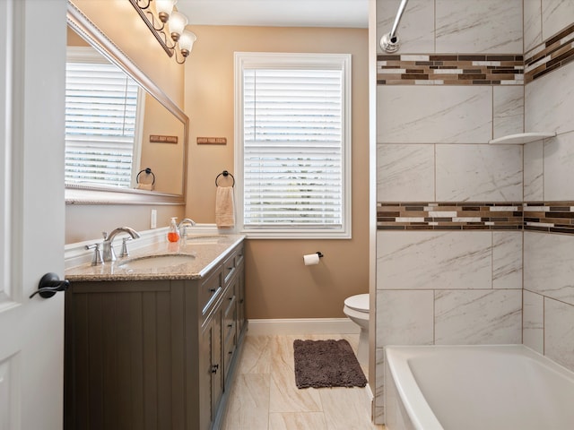 bathroom featuring marble finish floor, toilet, vanity, a wealth of natural light, and baseboards