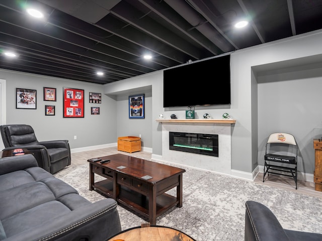 living area featuring recessed lighting, a glass covered fireplace, wood finished floors, and baseboards
