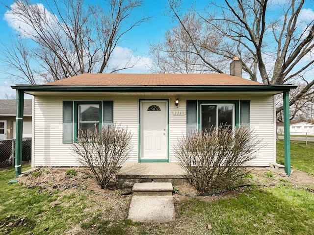 single story home with a front yard, a porch, and a chimney