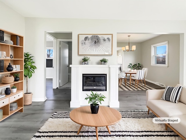 living area with a chandelier, baseboards, dark wood finished floors, and visible vents