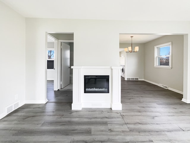 unfurnished living room with visible vents, washer / dryer, and wood finished floors