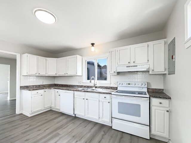 kitchen featuring white cabinets, a sink, dark countertops, white appliances, and under cabinet range hood