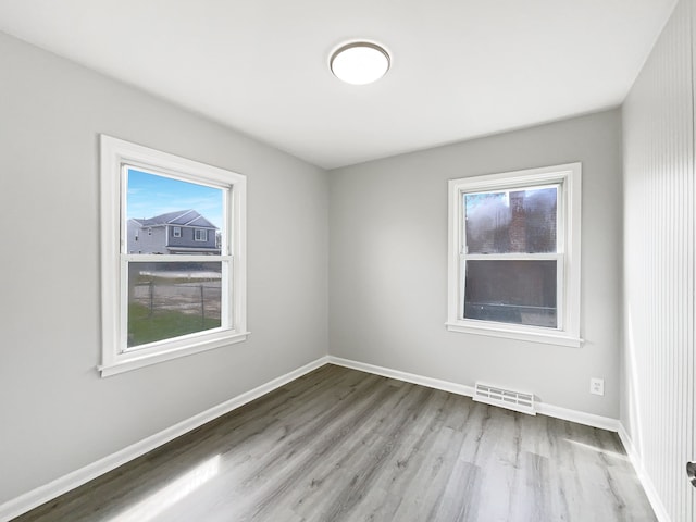 spare room with visible vents, baseboards, and wood finished floors
