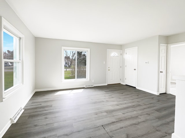 unfurnished living room with visible vents, baseboards, and wood finished floors