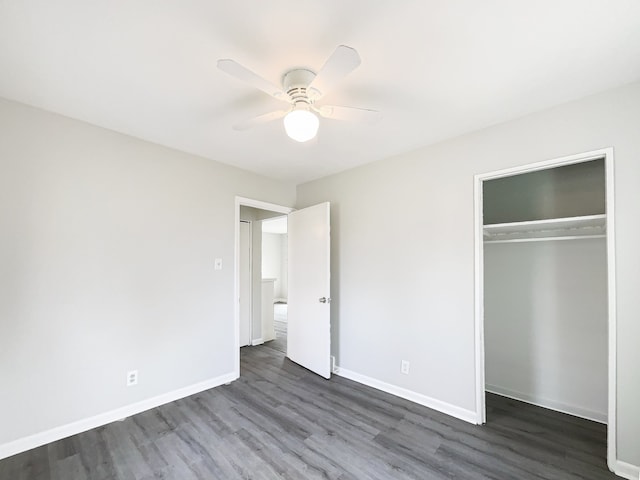 unfurnished bedroom featuring dark wood-style floors, a closet, baseboards, and a ceiling fan