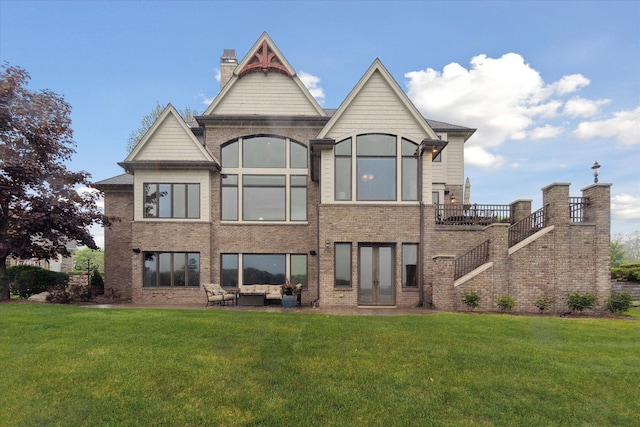 rear view of house with a lawn, an outdoor living space, and brick siding