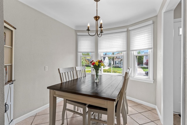 dining area featuring light tile patterned flooring, a chandelier, baseboards, and a textured wall
