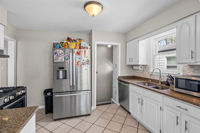 kitchen with appliances with stainless steel finishes, a sink, light tile patterned floors, and white cabinets