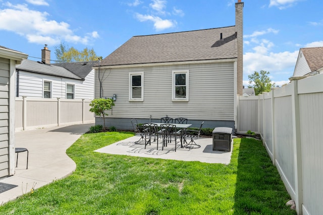 back of house with a patio, a shingled roof, and a chimney