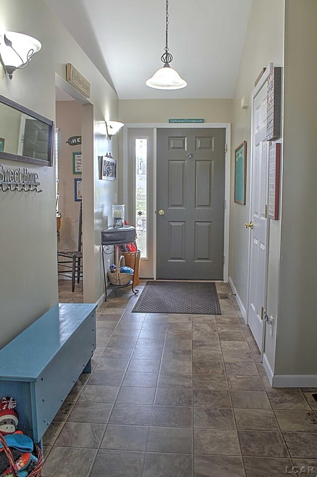 foyer with stone finish floor, vaulted ceiling, and baseboards