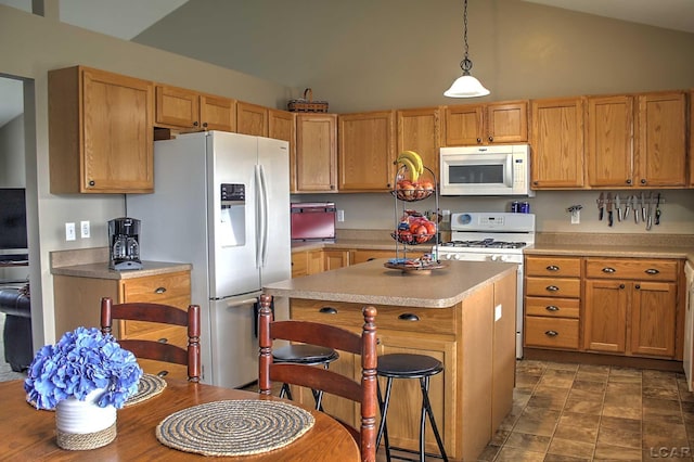 kitchen featuring a breakfast bar area, lofted ceiling, white appliances, and a kitchen island