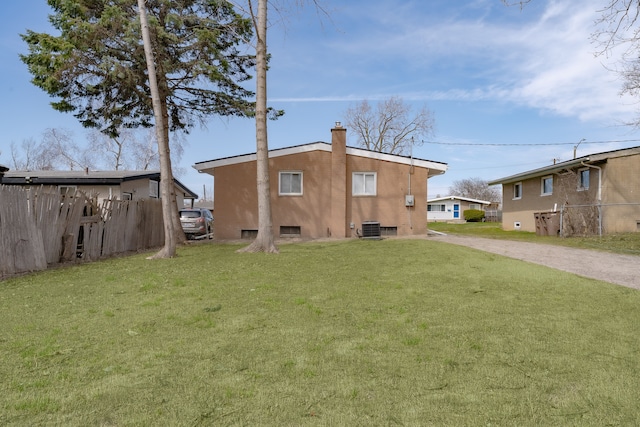 1182 Dudley Ave, Pontiac, MI 48342 - back of house featuring dirt driveway, a yard, fence, a chimney, and central AC unit