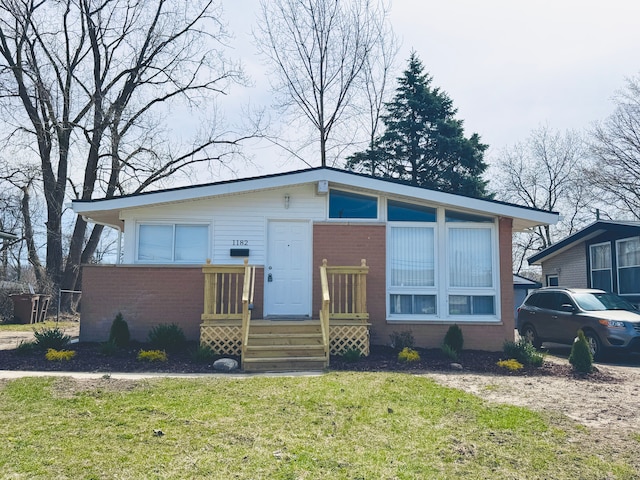 1182 Dudley Ave, Pontiac, MI 48342 - view of front of house with brick siding, a deck, and a front lawn