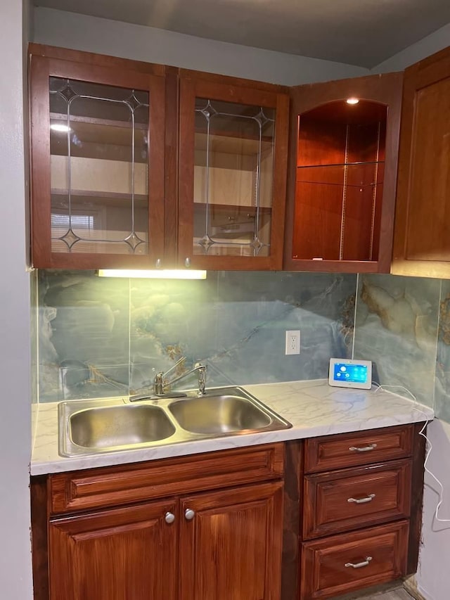 kitchen featuring brown cabinetry, tasteful backsplash, light countertops, and a sink