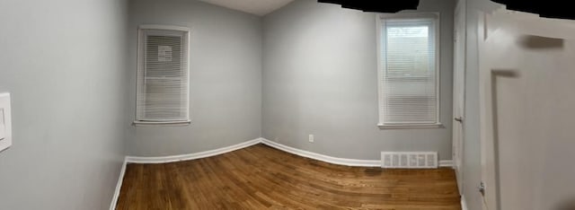 empty room with visible vents, baseboards, and wood finished floors