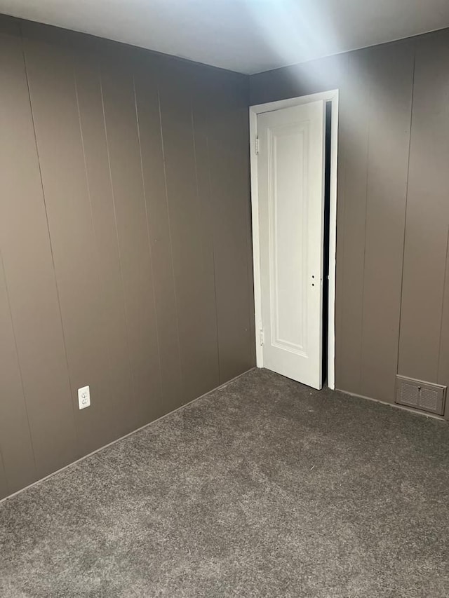 spare room featuring a decorative wall, carpet, and visible vents