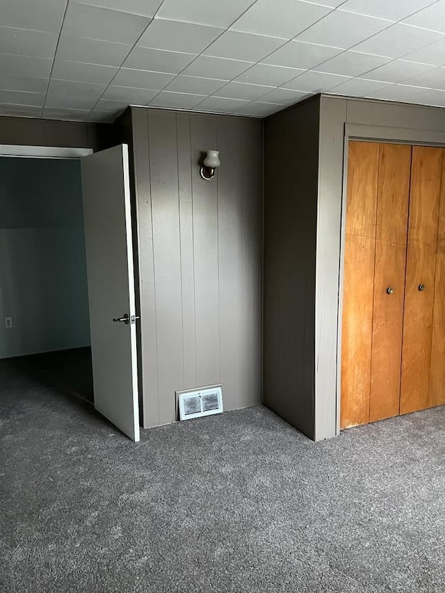 unfurnished bedroom featuring carpet flooring, a drop ceiling, and visible vents