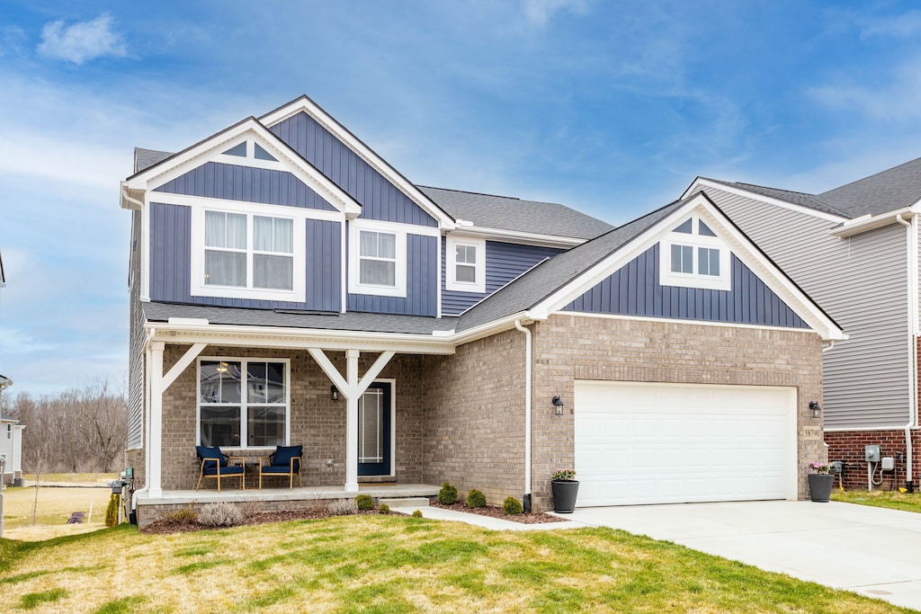 craftsman inspired home featuring a porch, an attached garage, board and batten siding, brick siding, and driveway