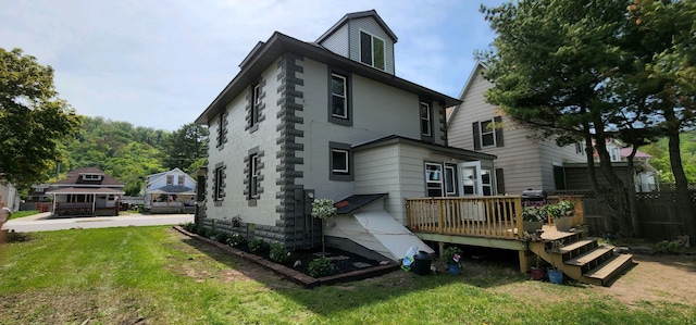 rear view of house with a deck and a lawn