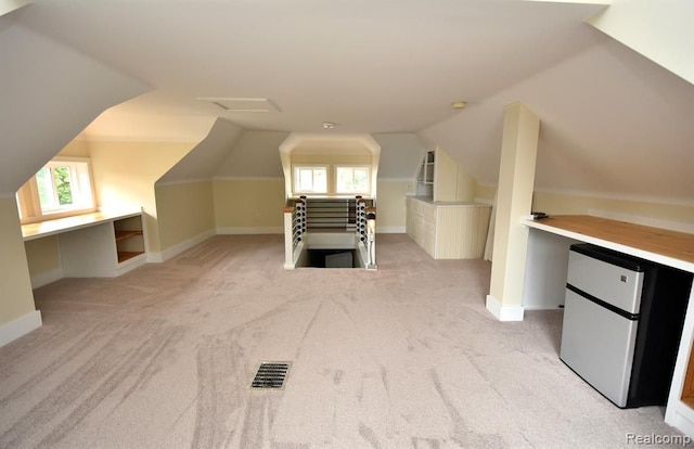 bonus room featuring light carpet, plenty of natural light, visible vents, and vaulted ceiling