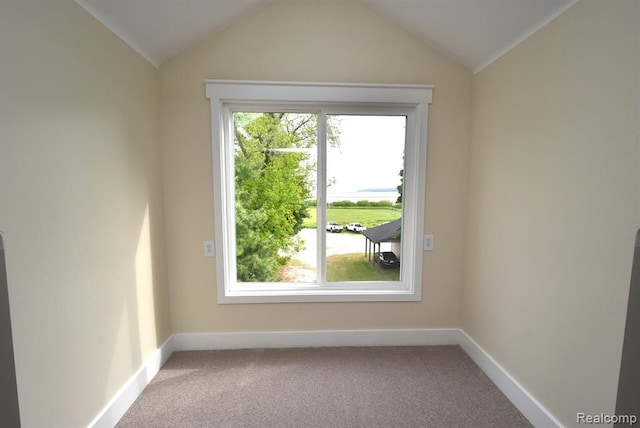 carpeted empty room with baseboards and vaulted ceiling