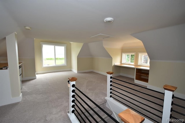 additional living space featuring carpet, baseboards, and vaulted ceiling