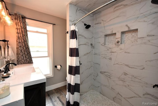 bathroom featuring a marble finish shower, baseboards, vanity, and wood finished floors