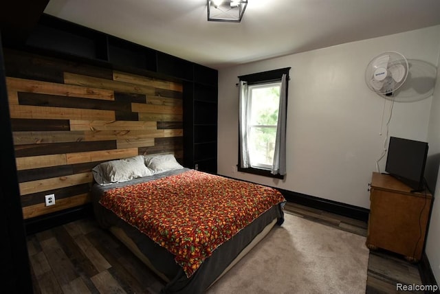 bedroom featuring wood finished floors and wood walls