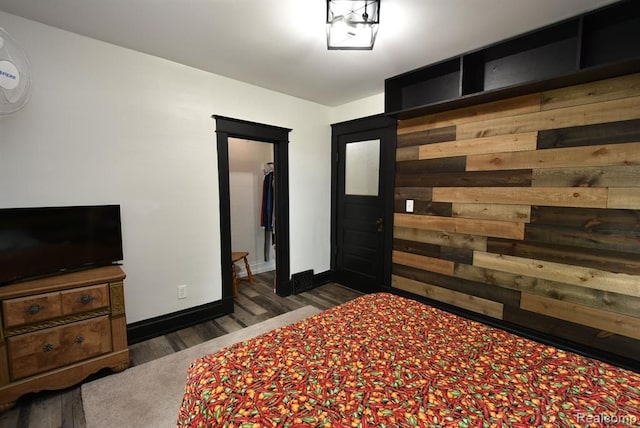 bedroom with wood walls, baseboards, and wood finished floors