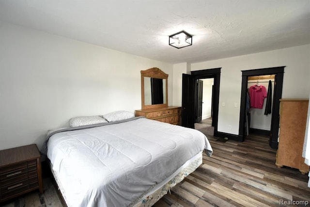 bedroom featuring a closet, baseboards, a walk in closet, and wood finished floors