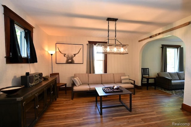 living room with baseboards, arched walkways, and dark wood finished floors